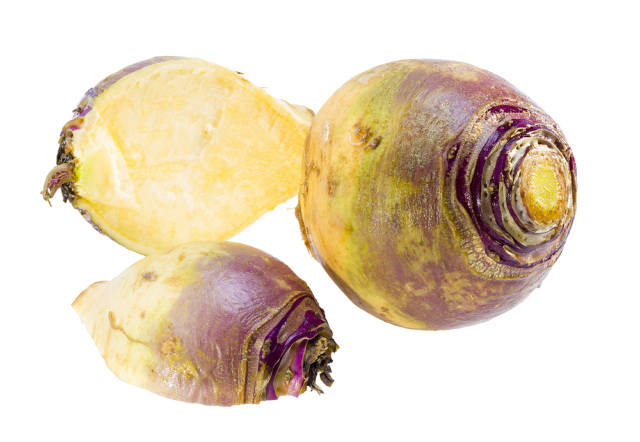 Rutabaga root crop cut in half with yellowish purple skin and yellowish flesh.