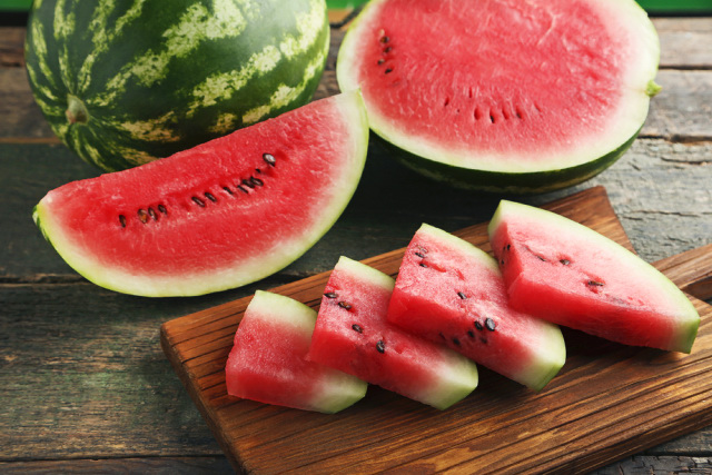 Sliced watermelons on the table and on a wooden chopping board.